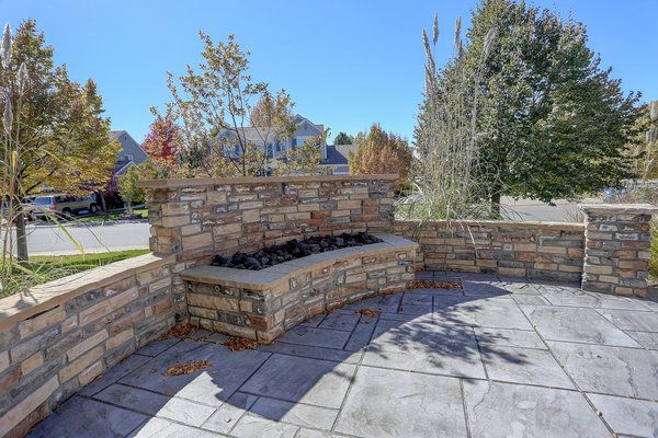 Stamped concrete patio with stone wall and stone gas fireplace