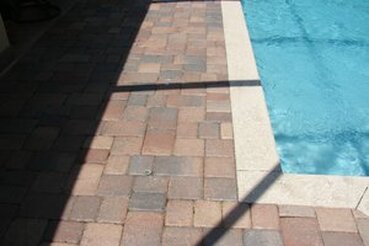 Multi-colored, mixed size, brick paver patio surrounding pool